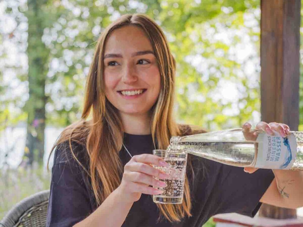 Person gießt Mineralwasser in ein Glas