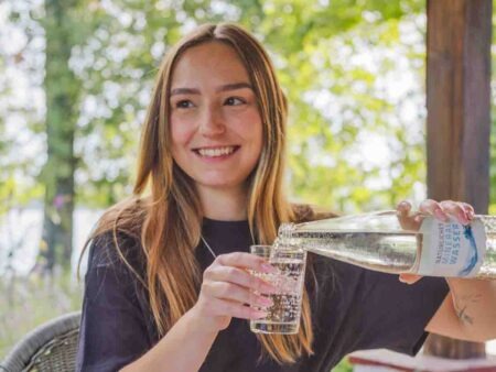 Person gießt Mineralwasser in ein Glas