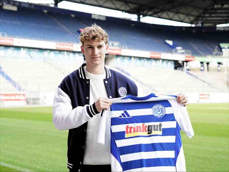 Dominik Kother, hält ein Trikot vor sich